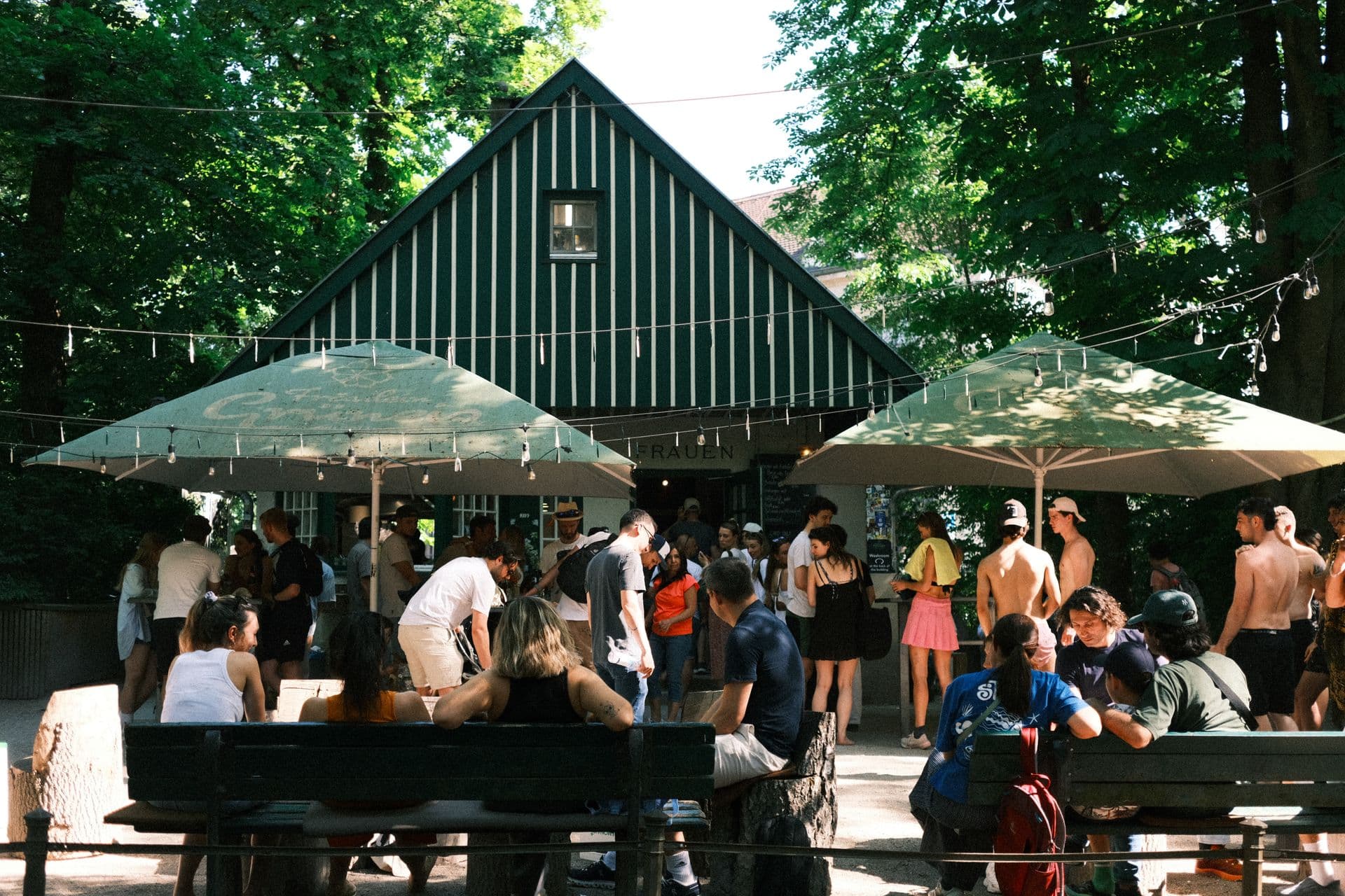 Le jardin en fin d'après-midi, tables longues pleines, guirlandes allumées